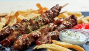 four pork skewers with fries and tzatziki