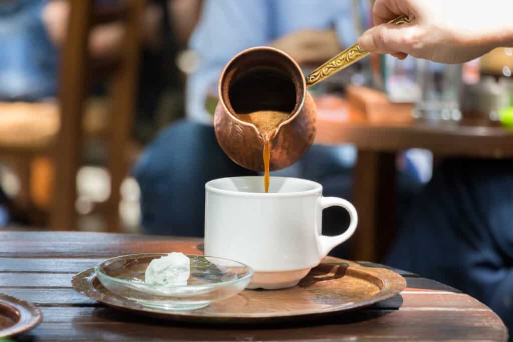 Greek coffee is poured in a cup with aturkish delight on a crystal plate