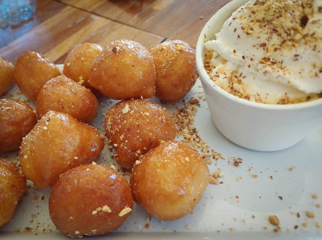 Loukoumades the traditional Greek pastry consisting of a deep-fried dough ball covered with honey and walnuts served on a white plate with yoghurt